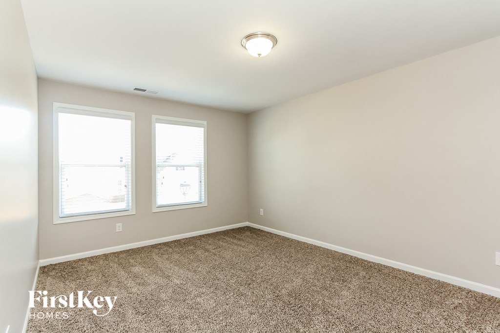 a empty room with carpet and two windows