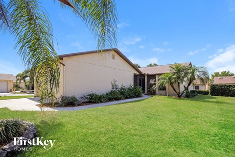 A house with a well-manicured lawn and a clear blue sky above.