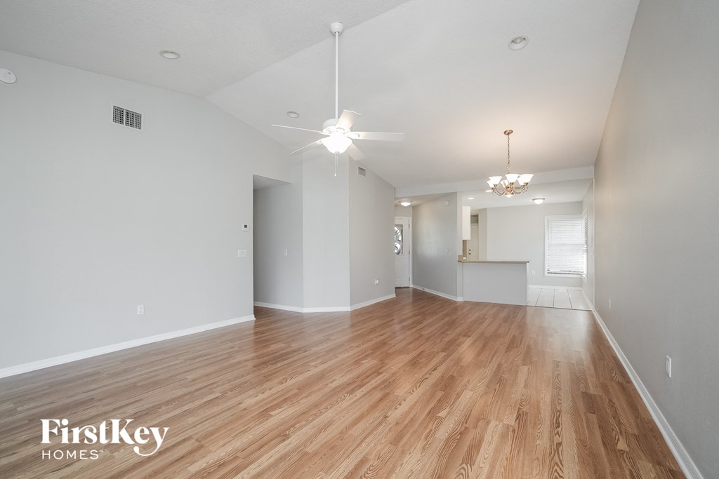 A spacious room with wooden floors and a chandelier hanging from the ceiling.