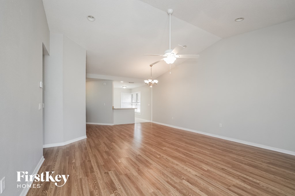 A spacious room with wooden flooring and white walls.