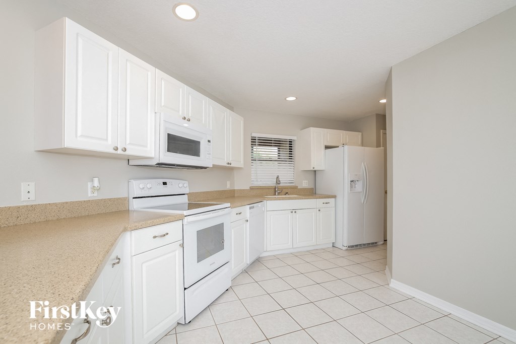 A kitchen with white appliances and cabinets.