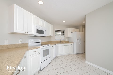 A kitchen with white appliances and cabinets.