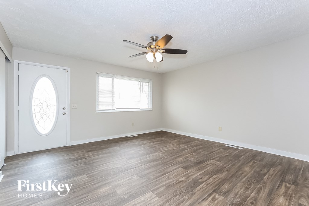 A room with a ceiling fan and wooden flooring.