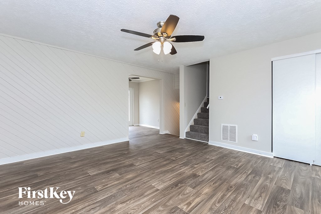 A room with a ceiling fan and wooden flooring.