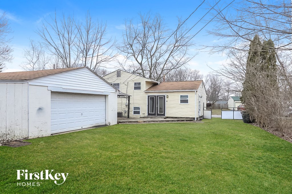 A white garage is attached to a house with a brown roof.