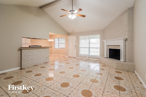 A spacious living room with a fireplace and a fan.