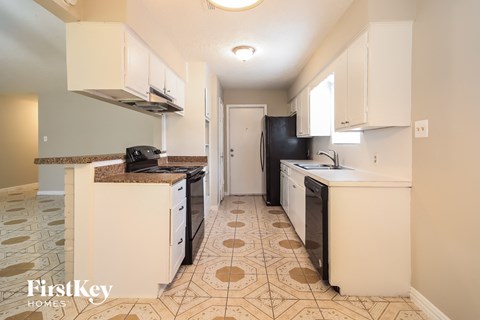 A kitchen with a tile floor and a refrigerator in the background.