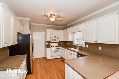 A kitchen with wooden cabinets and a black fridge.