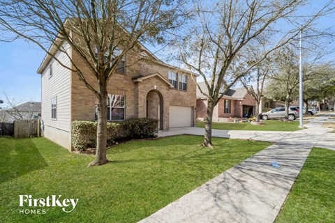 the front of a house with a driveway and lawn and trees