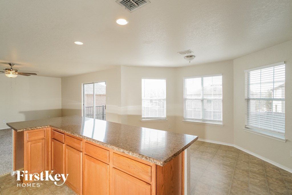 an empty kitchen with a granite counter top and some windows