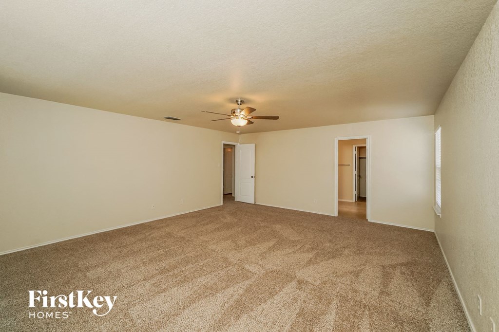 a spacious living room with carpet and a ceiling fan