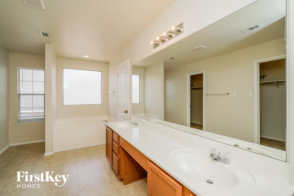 the master bathroom has a large vanity with a sink and a large mirror