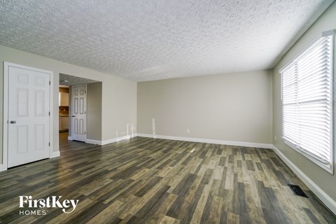 the spacious living room with wood flooring and white walls