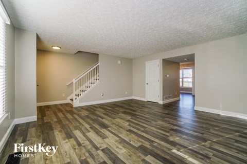 the living room and dining room of an empty house with wood flooring