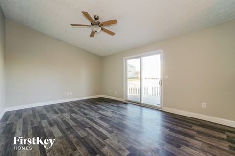the spacious living room with hardwood flooring and a ceiling fan