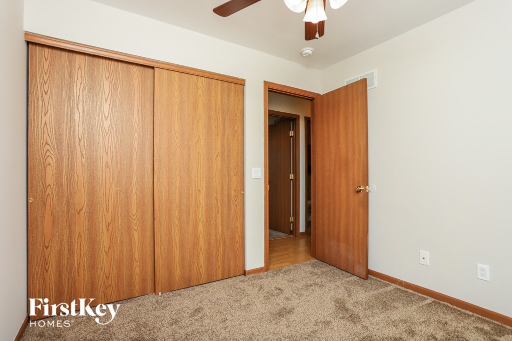 a bedroom with two closet doors and a ceiling fan