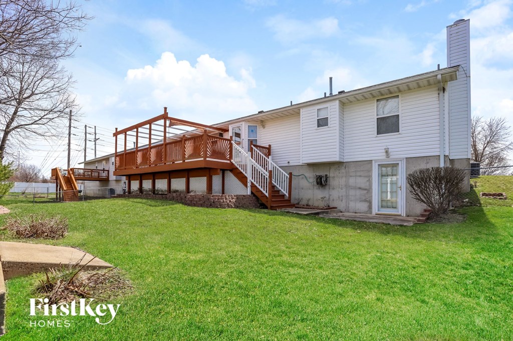 a white house with a deck on top of a green yard