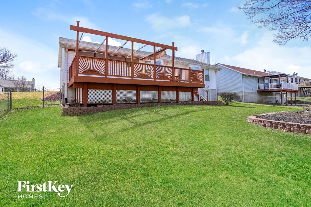 a home with a deck on top of a green yard
