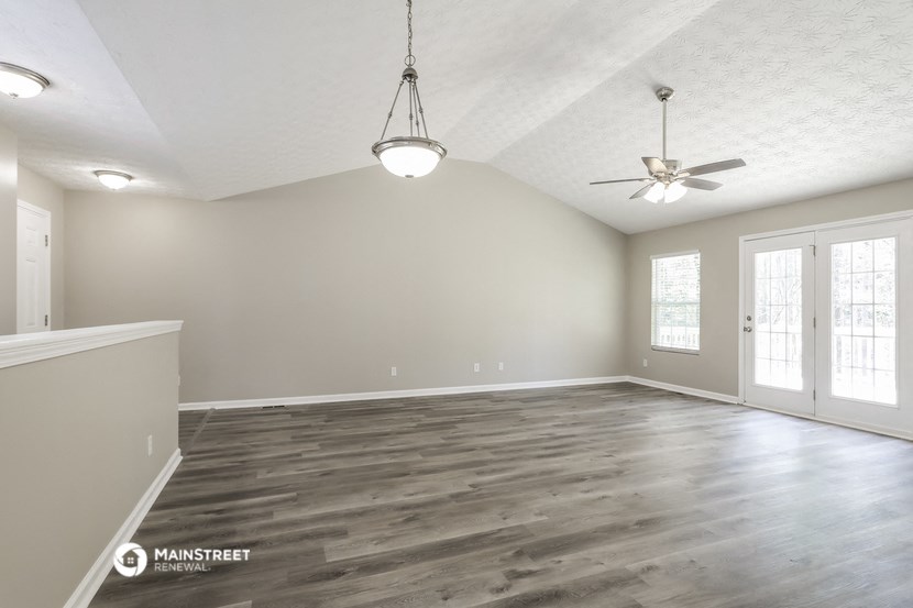the spacious living room with wood flooring and a ceiling fan