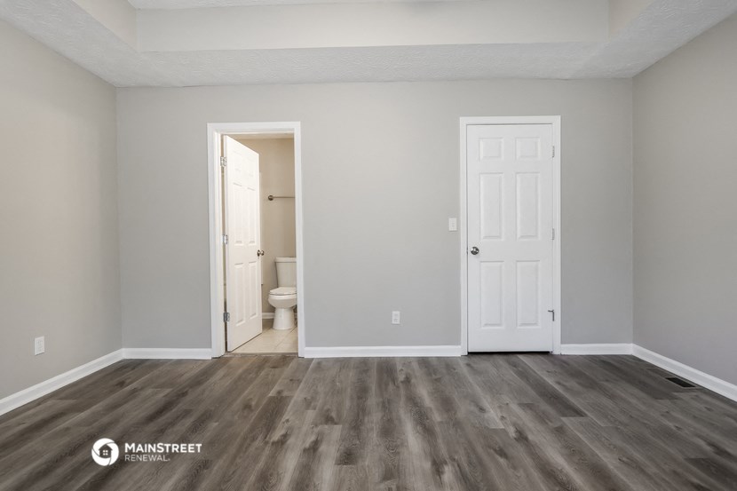 the spacious living room of an apartment with a door to the bathroom