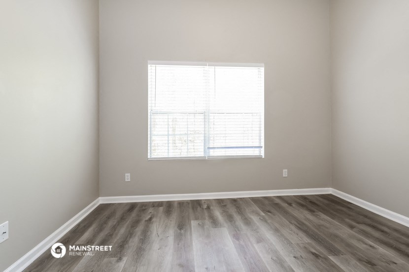 an empty room with wood floors and a window