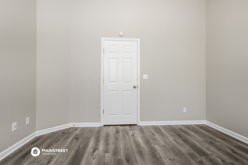 a room with wooden floors and a white door