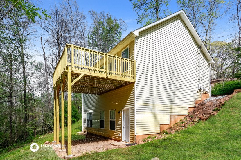 a white house with a yellow deck on top of a hill