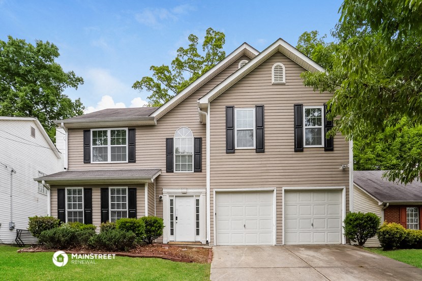 a beige house with two garage doors and a lawn