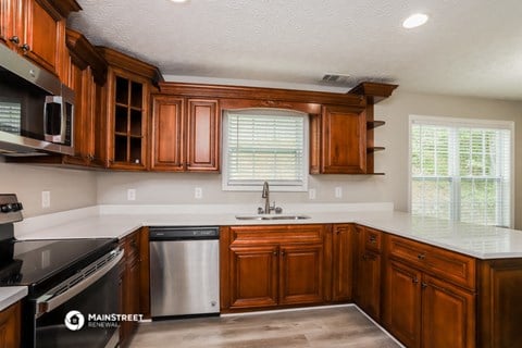 a kitchen with wooden cabinets and white counter tops and a sink