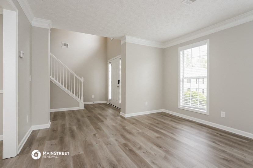 the spacious living room with hardwood floors and a staircase