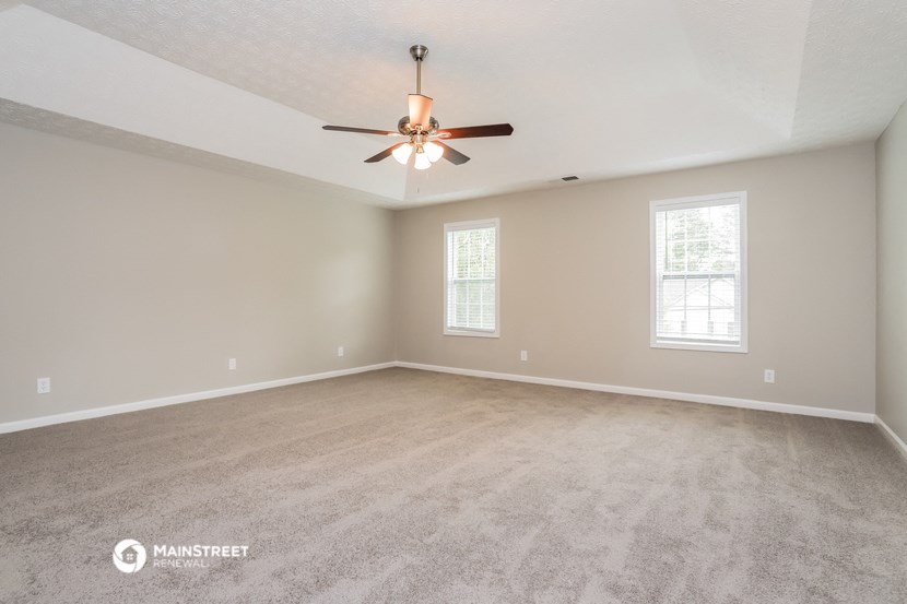 the spacious living room with carpeting and a ceiling fan
