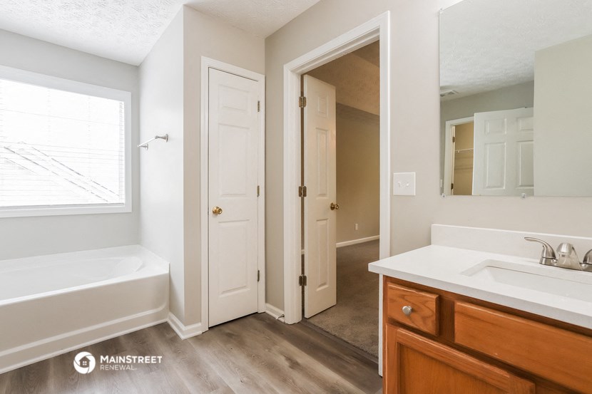 a bathroom with a tub and a sink and a mirror