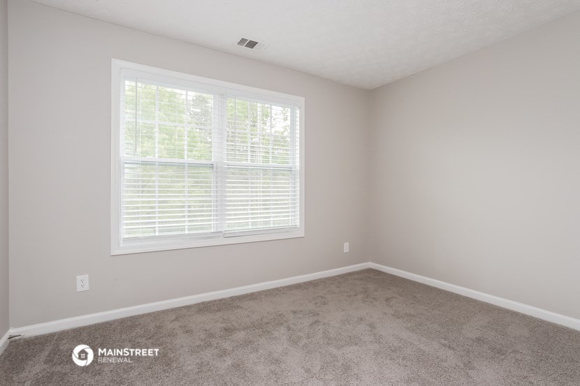 a bedroom with carpet and a large window