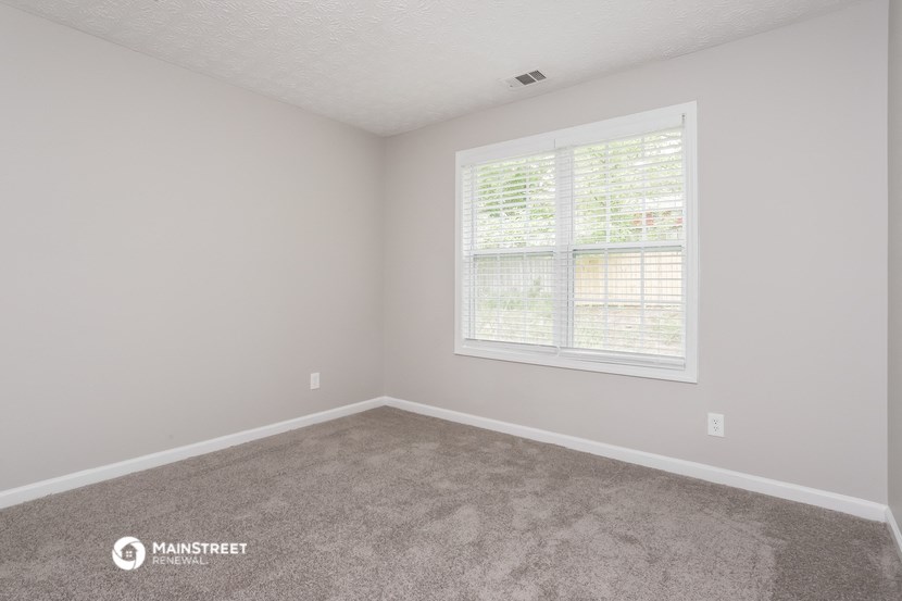 a bedroom with carpet and a large window