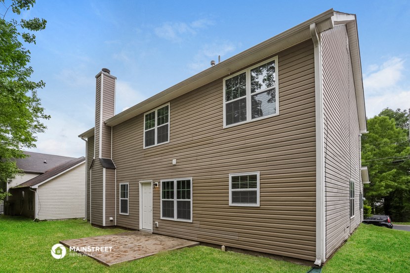 a view of the back of a house with a garage and a yard