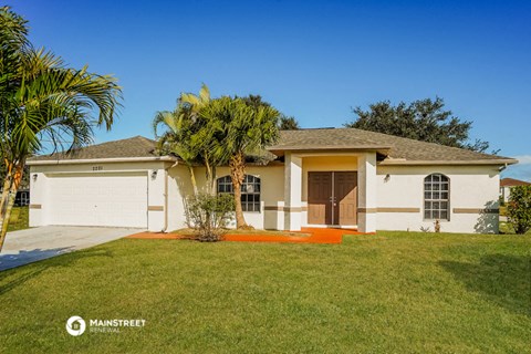 a beige house with a palm tree in front of it