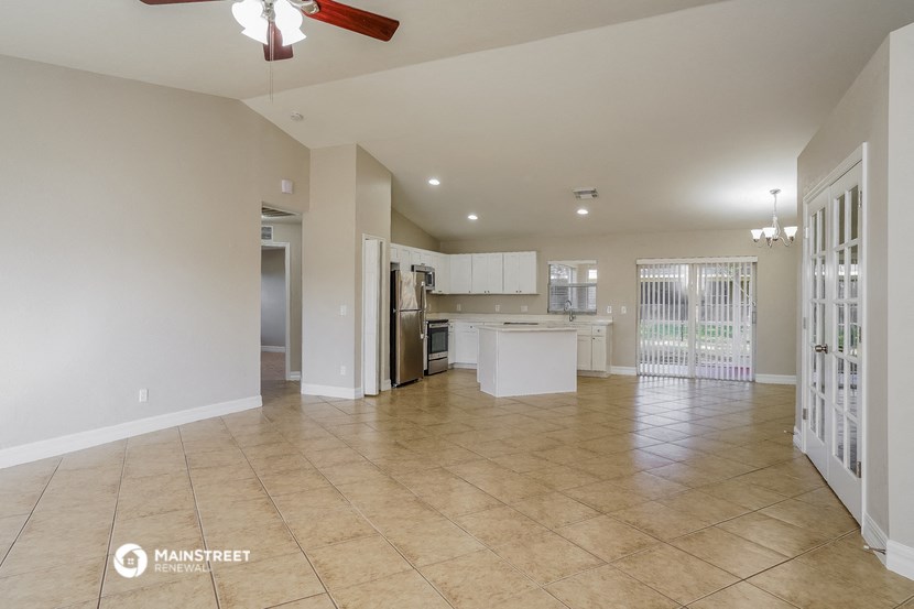 an open kitchen and living room with tile flooring