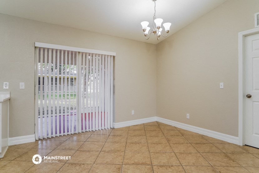 the living room of a home with a large window with white blinds