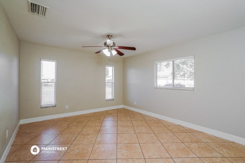 an empty living room with a ceiling fan and a tiled floor