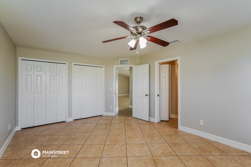 the living room has a ceiling fan and tile floors