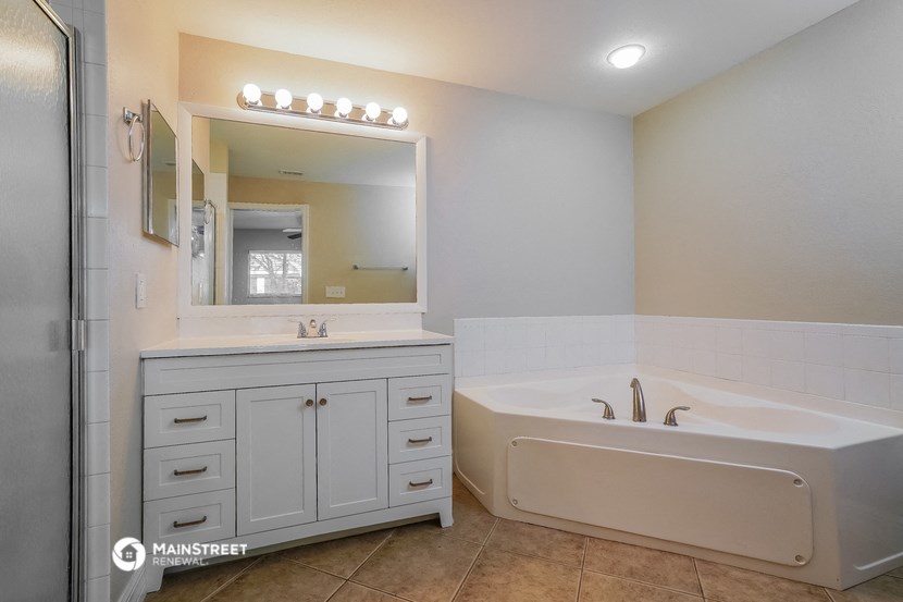 a bathroom with a tub and a sink and a mirror