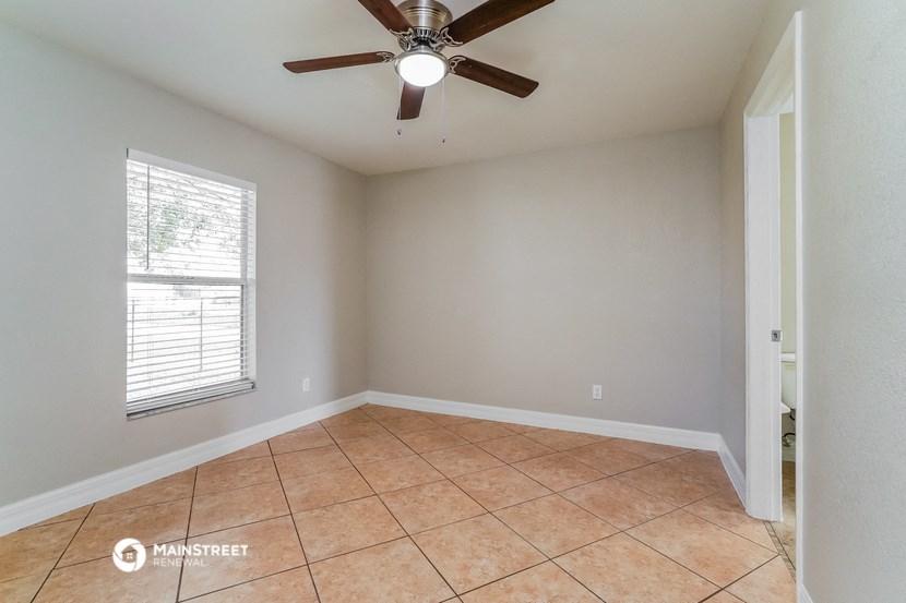 the living room of an empty home with a ceiling fan