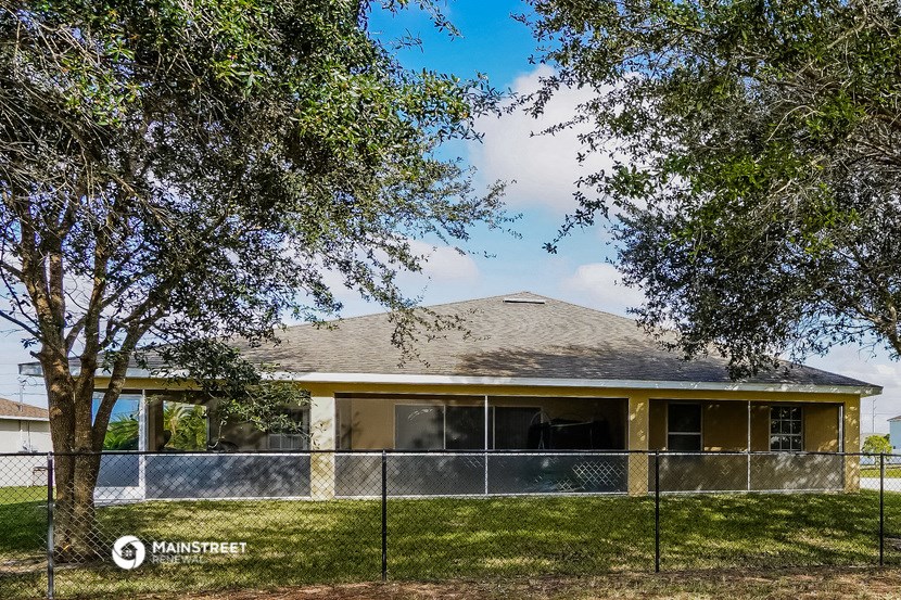 a house with a fence and trees in front of it
