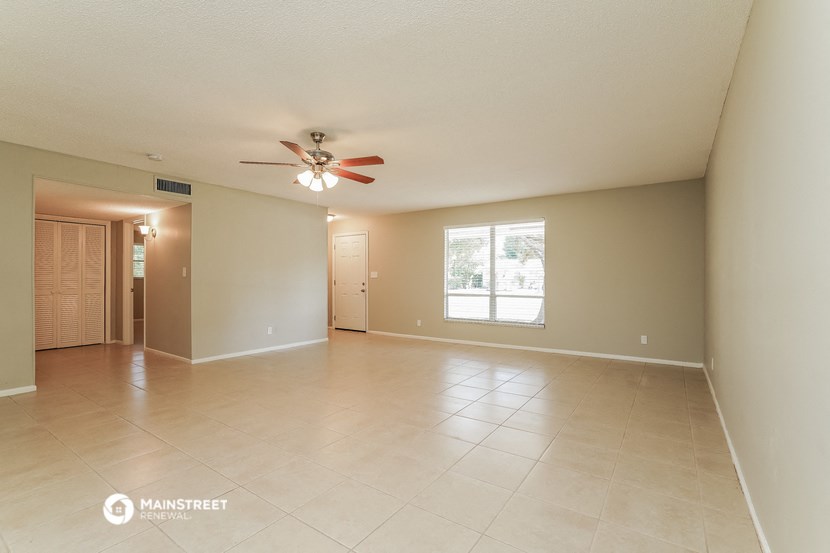 an empty living room with a ceiling fan and tiled floors