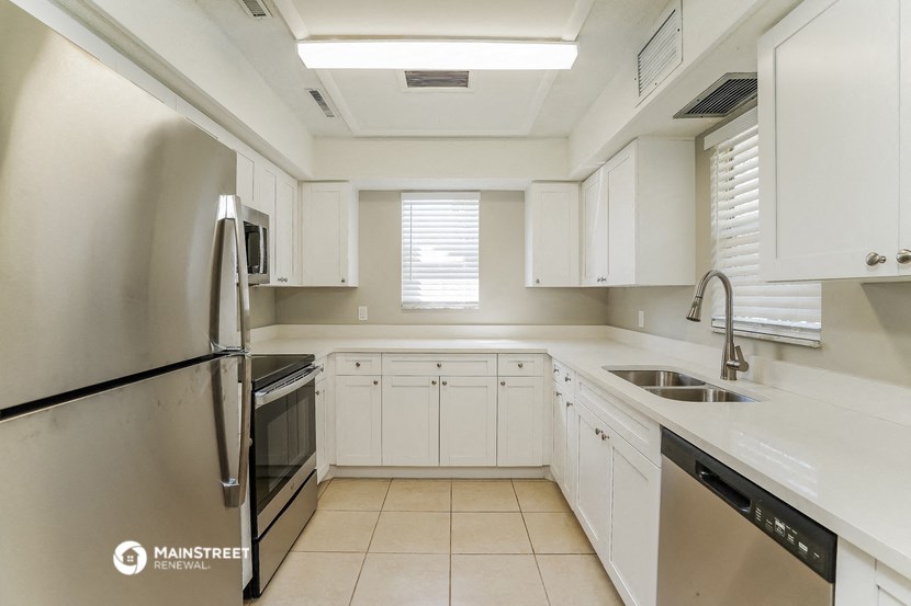 a kitchen with white cabinets and a sink and a refrigerator