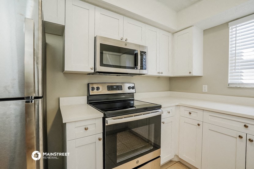 a kitchen with white cabinets and stainless steel appliances and a microwave