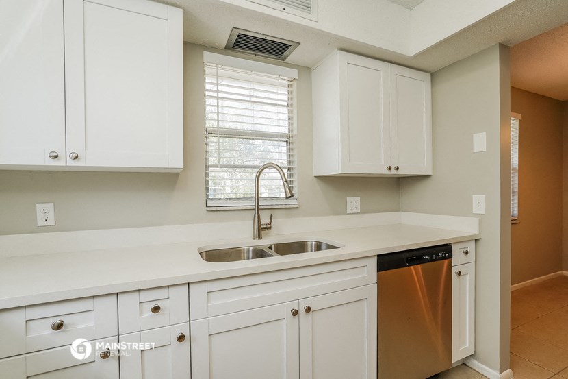 a kitchen with white cabinets and a sink and a window