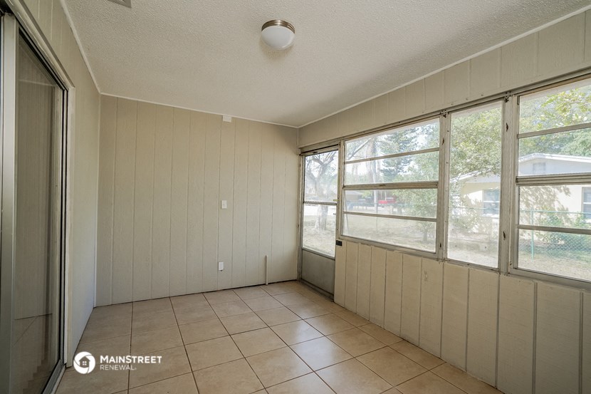 the living room of a home with large windows and a tiled floor