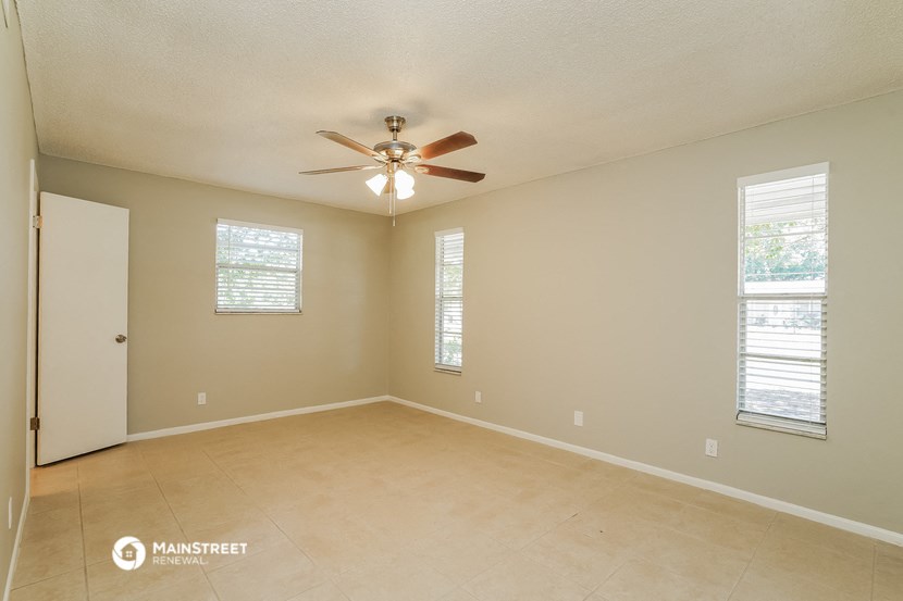 the spacious living room with ceiling fan and tiled floor