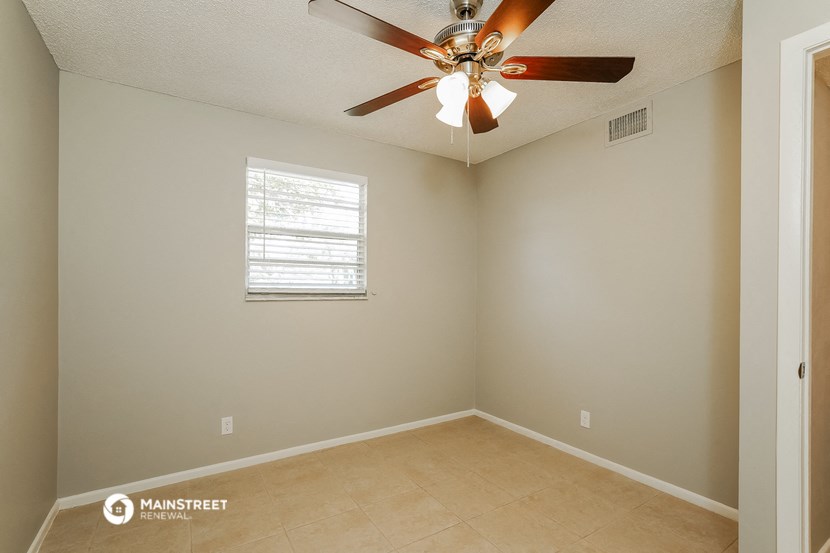 the spacious living room has a ceiling fan and a tiled floor